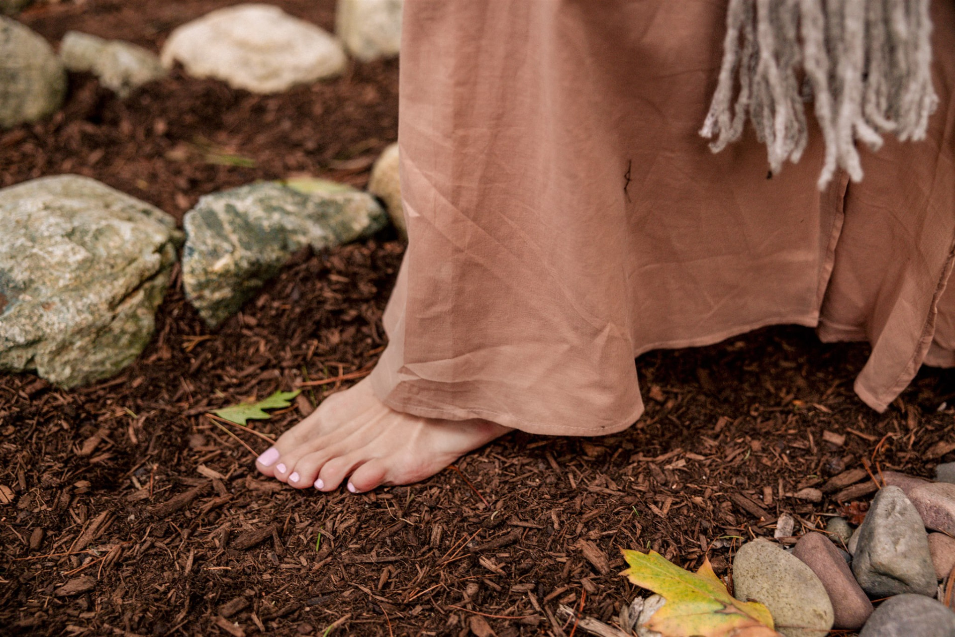 A bare foot stepping onto earth and mulch, grounding into the land.