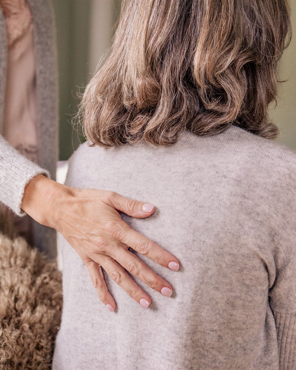 A healing hand rests gently on the back — a breathwork session in stillness.