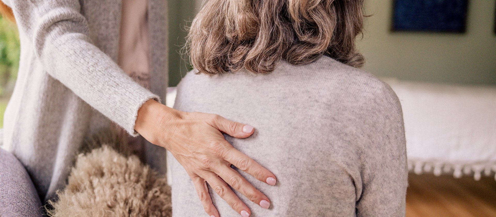 A healing hand rests gently on the back — breathwork in stillness.